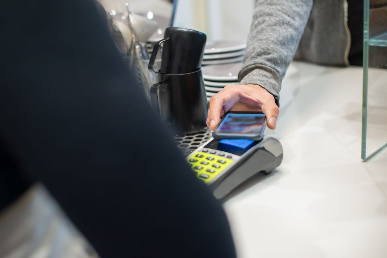 A customer tapping a phone against a card terminal at a counter